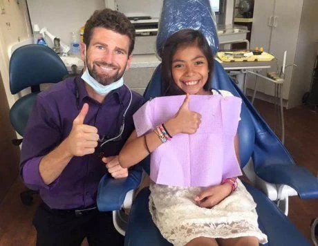 Dr. Miller and a young patient giving a thumbs up from the dental chair.