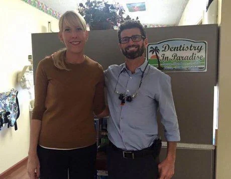 Dr. Kevin Miller and a colleague beside a Dentistry in Paradise sign.