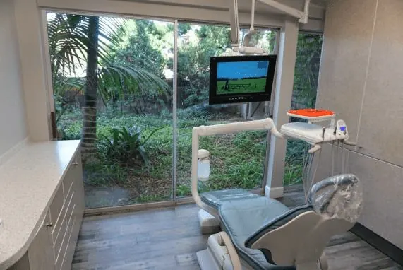 A treatment room in Suite 109 with a ceiling-mounted screen and a garden outside the window.